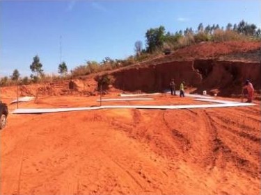 Terreno de terra vermelha com a marcação da obra do reservatório elevado, antes da construção